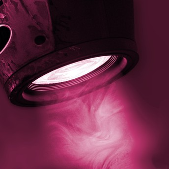 A light spotlight, shining through light smoke, colourised in purple