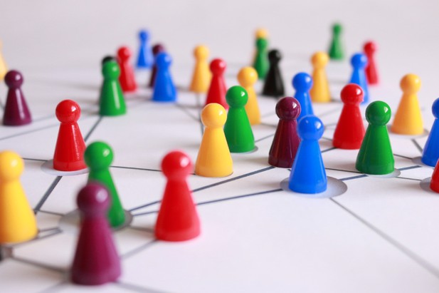 Colourful board game pieces sit on an illustration of a  network showing the interconnectedness of people.