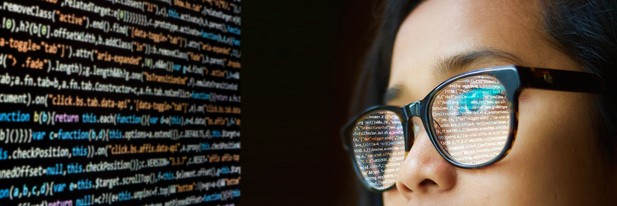 person with glasses stares at a screen containing code