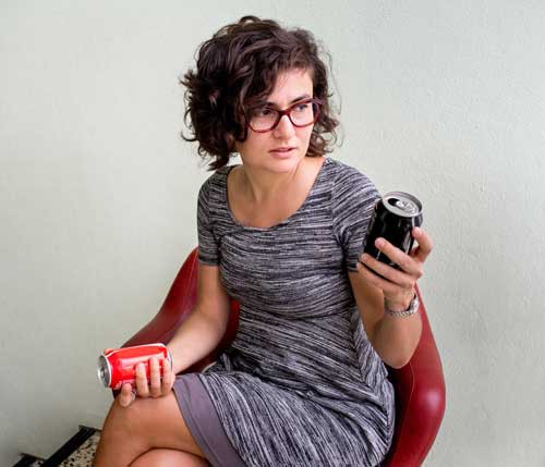 Ana Domigos holding 'diet' and 'regular' soft drink cans.