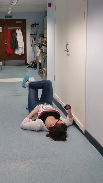 Hazel Lowe lying on the lab floor while waiting for the vacuum chamber to pumpdown during an experiment