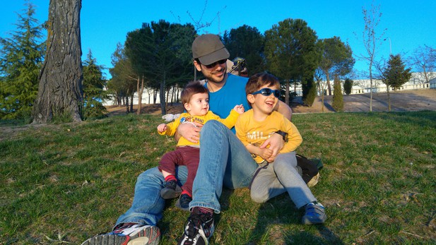 Modesto Redrejo-Rodriguez sitting on the grass, holding his sons